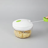 White and green manual mini food chopper and garlic press sitting on a kitchen counter.